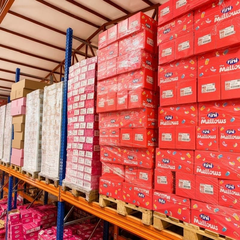 Yüksek raflara paletlerle istiflenmiş şekerleme kolileri